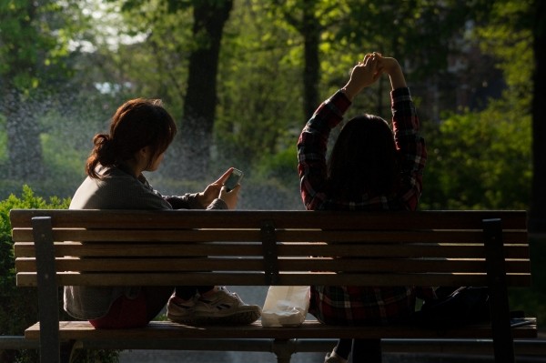 female-friends-relaxing-on-bench-in-park